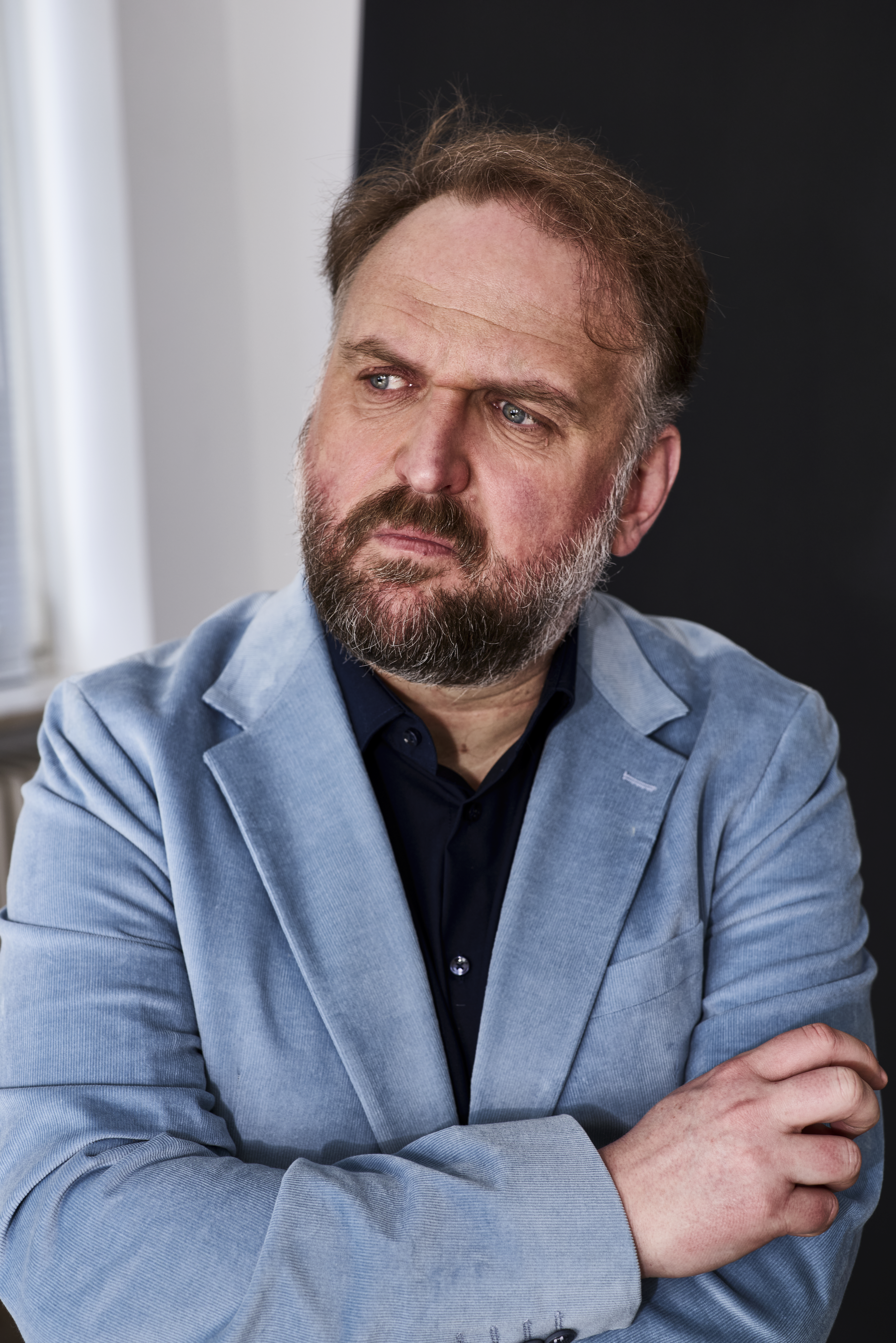Ronny Schuster mit seitlichem Blick und blauen Cord Anzug.