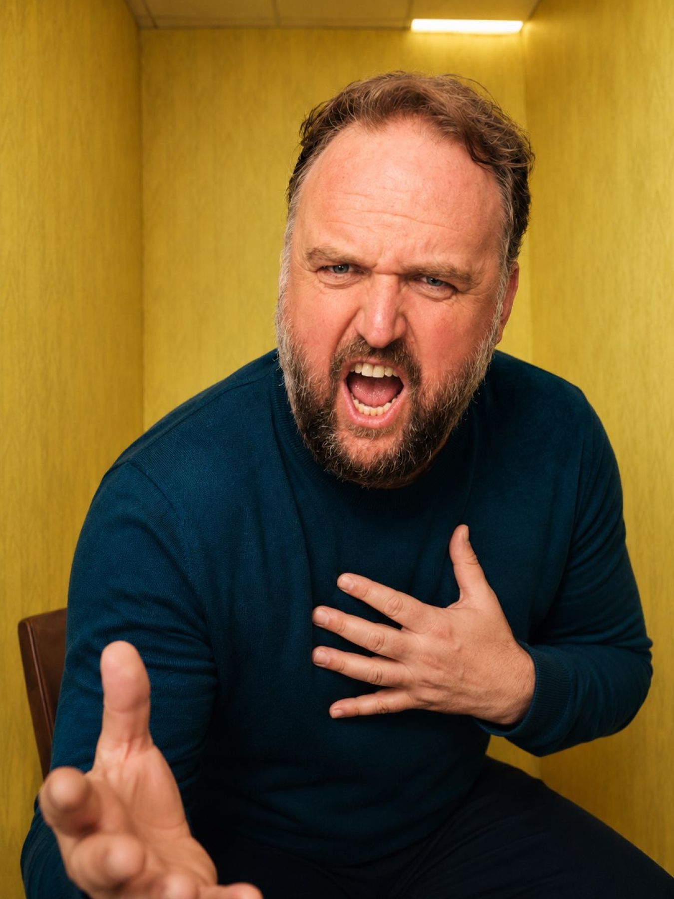 Ronny Schuster gestikuliert ausdrucksstark mit einer Hand auf der Brust.