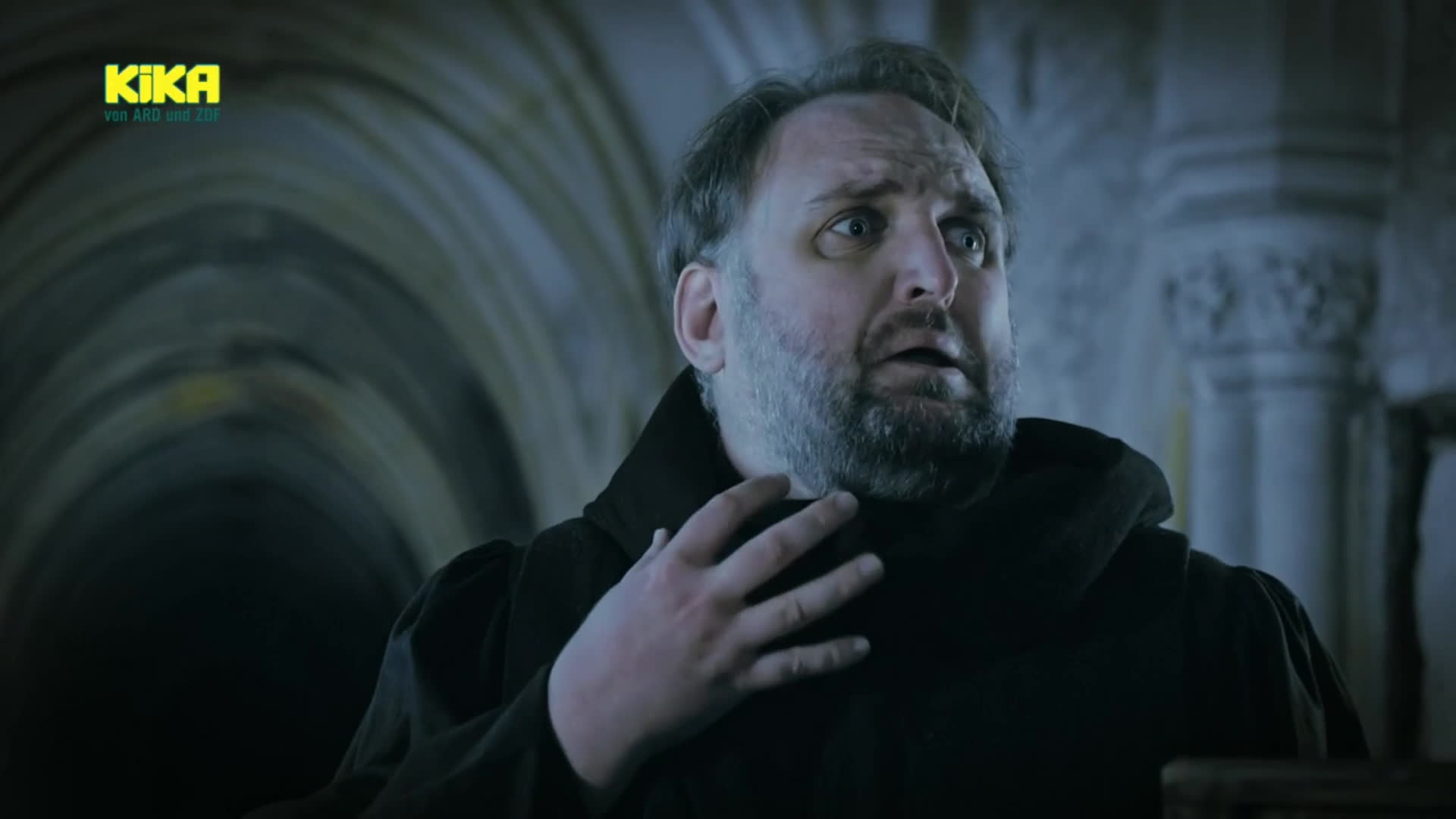 Ronny Schuster in dunkler historischer Kleidung mit nach oben gerichtetem Blick.