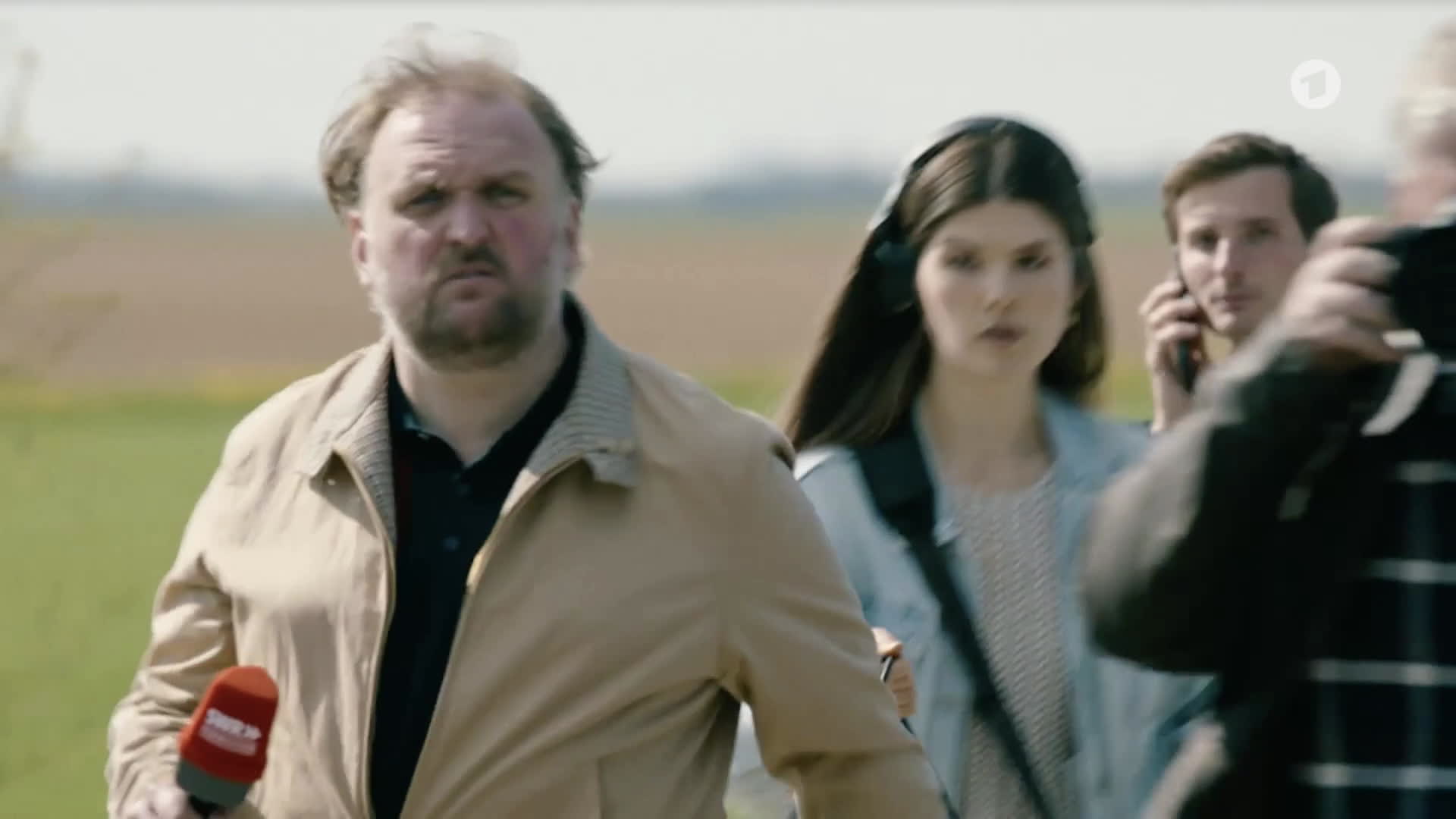 Ronny Schuster als Journalist mit Mikrofon im Freien.